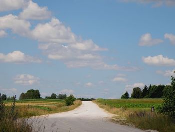 Road amidst agricultural field against sky