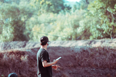 Man holding mobile phone while looking away outdoors