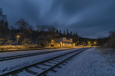 Railroad tracks by snow covered trees against sky