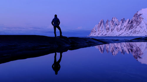 Silhouette man standing by sea against sky