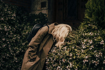 Blonde woman model wearing a raincoat, lying on the tree.