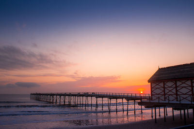 Pier over sea against sky during sunset