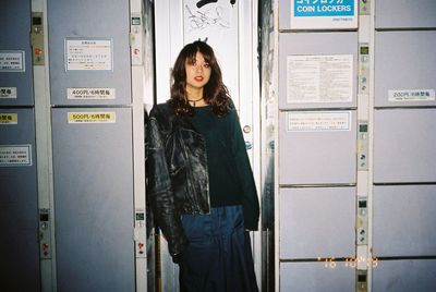 Portrait of young woman standing against wall