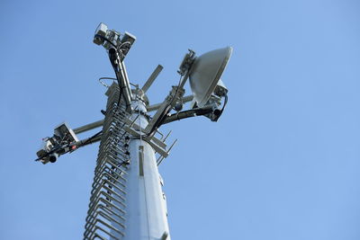 Low angle view of communications tower against clear blue sky