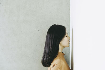 Woman with eyes closed standing by wall