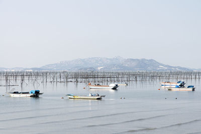 Boats moored on sea against clear sky