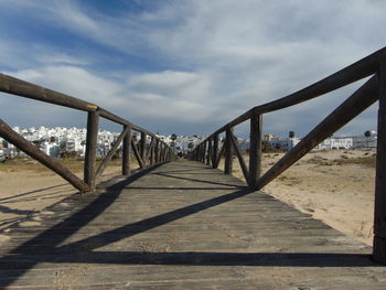 Footbridge over beach against sky