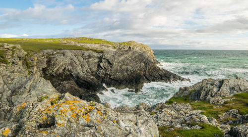 Rock formation by sea against sky