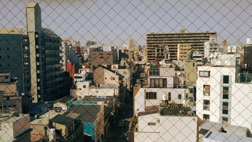View of residential buildings through chainlink fence