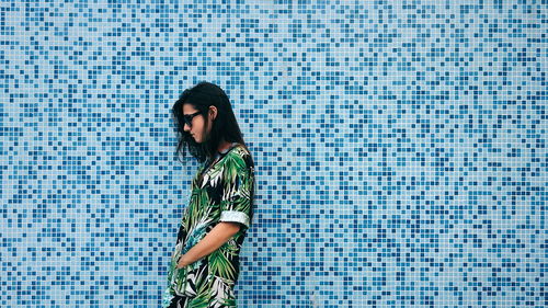 Side view of young woman standing by wall