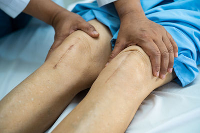 Cropped hands of doctor holding patients legs in hospital