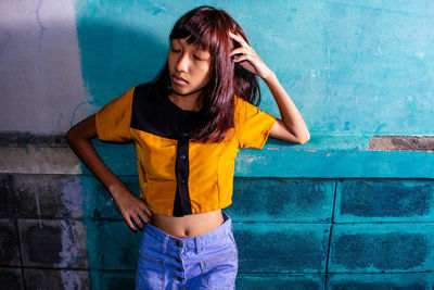 Portrait of young woman standing against wall