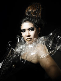 Fashion model dressed as witch against black background