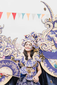 Portrait of a smiling young woman standing against wall