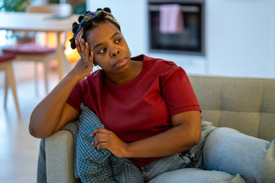 Young woman using mobile phone while sitting on sofa at home