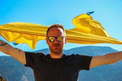 Low angle view of man with umbrella against clear blue sky