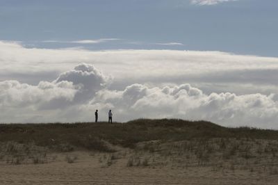 Men on landscape against sky