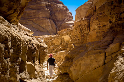 Rear view of man hiking on rock formation