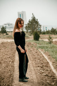 Young woman standing on road against sky