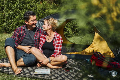 Happy couple relaxing in tent at camping during vacations. planning next trip with map. camp life