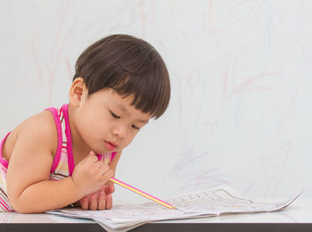 Boy looking away while holding paper on table