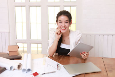 Young woman using phone while sitting on table