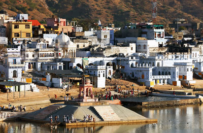 High angle view of people at temple by lake and white buildings