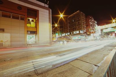 Light trails on city street by buildings at night