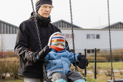 Grandfather swinging granddaughter in city