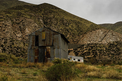 Abandoned house on field by mountain against sky