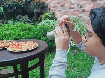 Teenage boy with camera, photographing pizza on the table