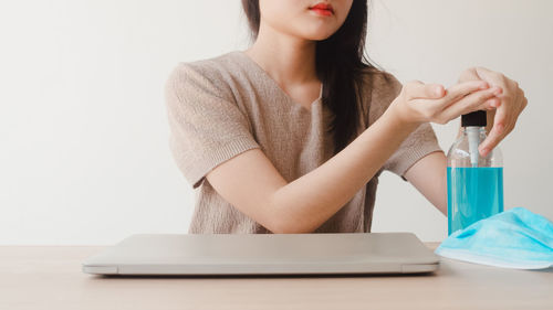 Midsection of woman holding smart phone while sitting on table