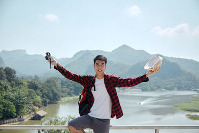 Full length of happy man standing on mountain against sky