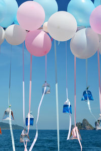Helium balloons flying with liquids in plastic bags against sea