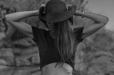 Mid adult woman wearing hat standing against rock formation