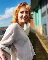 Portrait of young woman standing against building