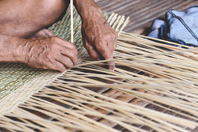 High angle view of craftsperson weaving straw basket