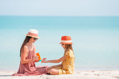 Mother and daughter sitting at beach