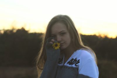 Portrait of young woman standing against sky during sunset