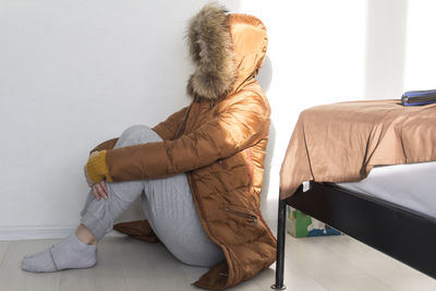 The girl turned away and sits on the floor in warm clothes.  energy crisis concept