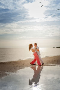 Young couple on beach against sky