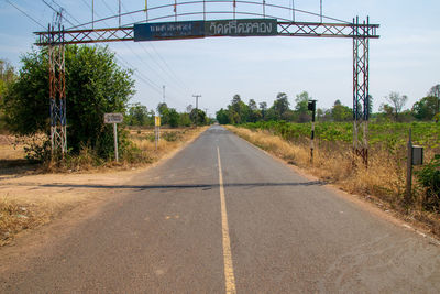 Empty road by trees against sky