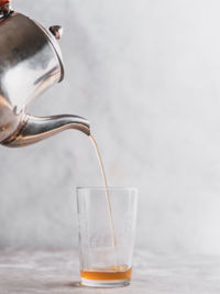 Close-up of moroccan mint tea being poured in glass on grey table