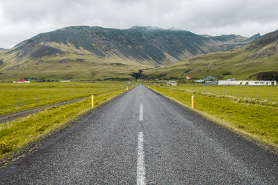 Road amidst field against sky