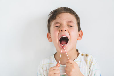 Cute boy pulling loose tooth using a dental floss. process of removing a baby tooth.