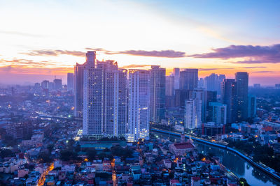 Aerial view of buildings in city against sky during sunset