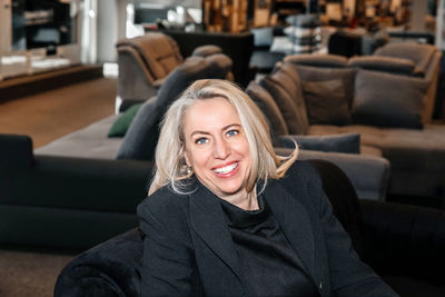 Joyful mature woman with bright silver hair, enjoying her time in a stylish furniture store