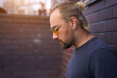 Man wearing sunglasses standing against wall