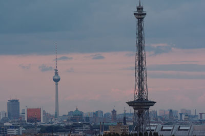 Communications tower in city against sky