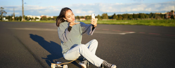 Side view of woman sitting on road